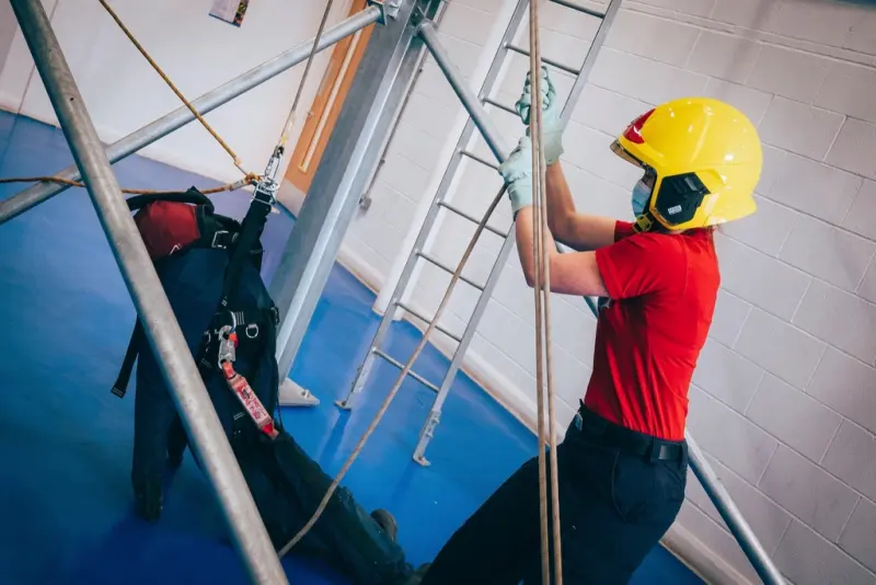 Trainee in a helmet and harness climbing a ladder during height-safety training