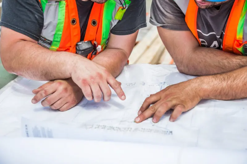 Workers in high-visibility vests reviewing site plans